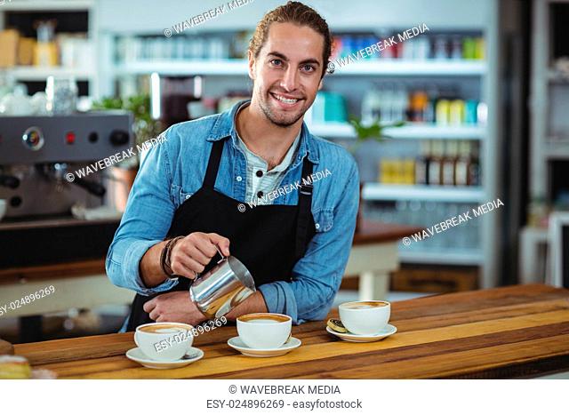 Portrait of waiter making cup of coffee at counter