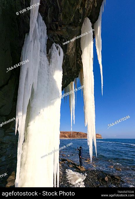 RUSSIA, VLADIVOSTOK - DECEMBER 4, 2023: A tourist stands by a rock covered with icicles in Bogdanovicha Bay of Russky Island. Yuri Smityuk/TASS