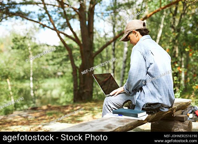 Young woman with laptop sitting on bench