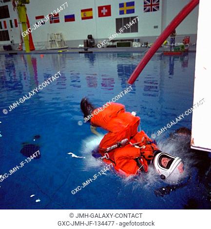 Astronaut Julie Payette, after sliding down a shuttle escape pole, splashes into the water during emergency bailout training