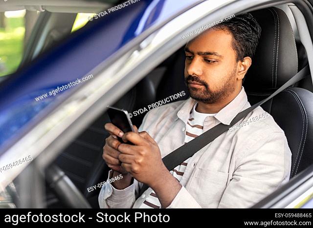 indian man in car using smartphone
