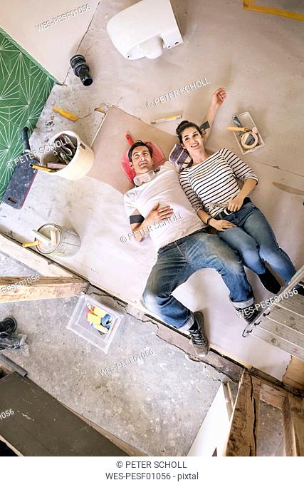 Happy couple renovating new home, taking a break, daydreaming