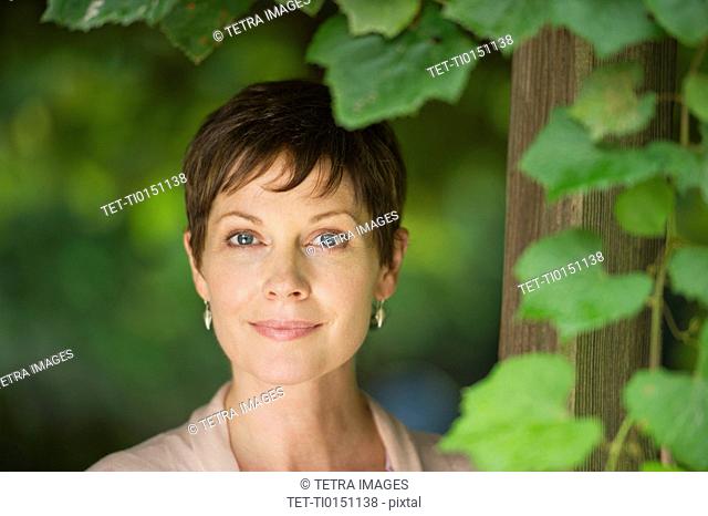 Portrait of mature woman standing next to ivy