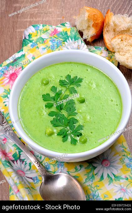 A plate of soup puree of green peas with parsley on a table