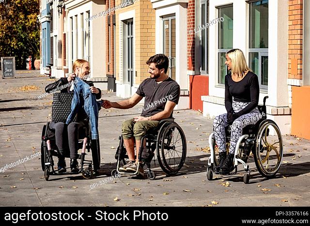 Three young paraplegic friends spending time together shopping outside in a city area; Edmonton, Alberta, Canada