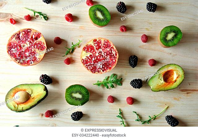 Aerial photo of raspberries, strawberries, avocado and kiwi on wooden background