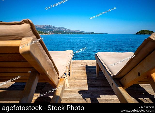 Ksamil, Albania Deck chairs on a pier overlooking the azure water