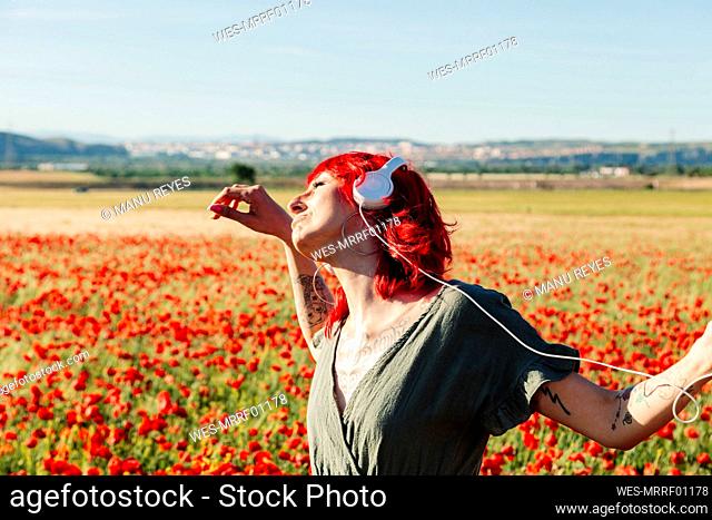 Carefree hipster woman dancing on poppy field