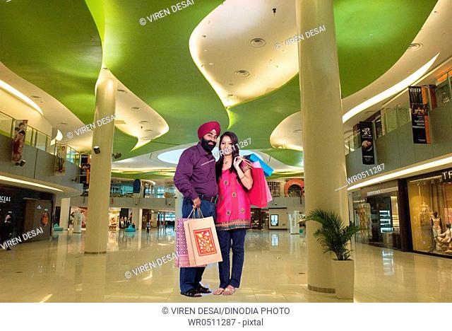 Sikh couple holding shopping bags standing in mall MR702Z, 779A
