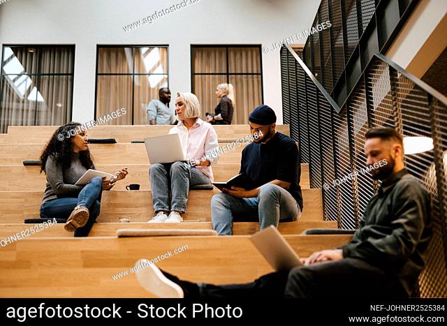 People relaxing on stairs in office building