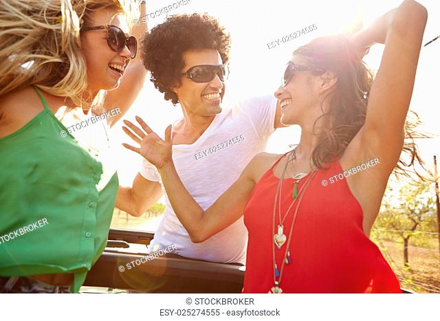 Group Of Young Friends Dancing In Back Of Open Top Car