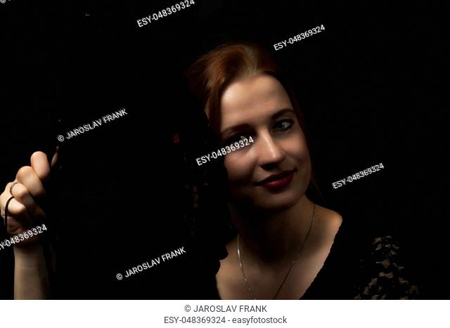 Low Key portrait of Flamenco Dancer young woman holding crochet black hand fan. All on the dark background
