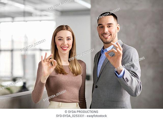 businesswoman and businessman showing ok at office