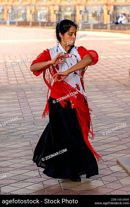 Seville, Spain - 10 January, 2021: passionate flamenco dancer woman in colorful clothes dancing at the Plaza de Espana in Seville