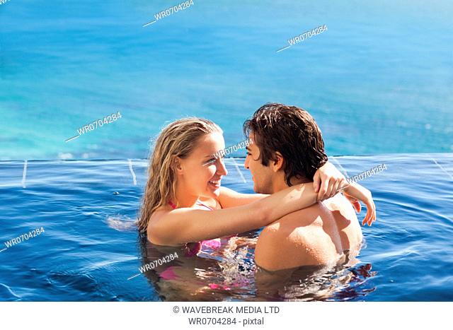 Side view of young couple hugging in the pool