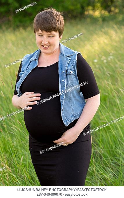 Maternity photo of a young woman with a short hair pixie cut in her third trimester with child
