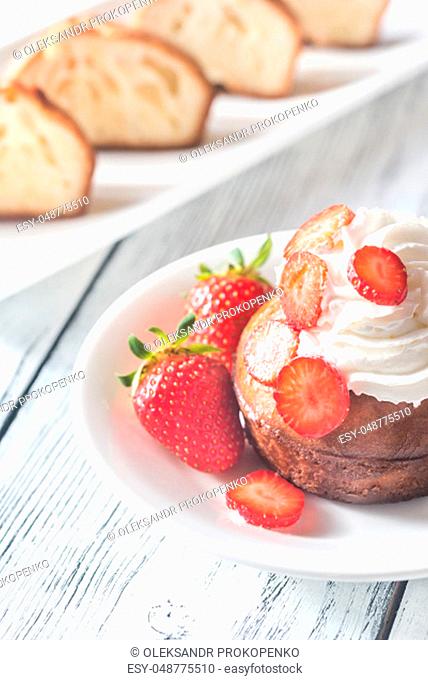 Rum baba decorated with whipped cream and fresh strawberries