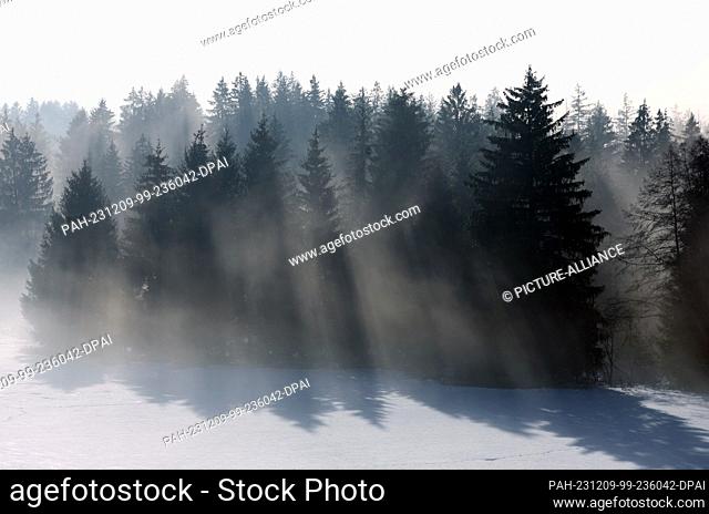 09 December 2023, Bavaria, Rettenbach: Rays of sunlight penetrate the fog in the wintry landscape. Photo: Karl-Josef Hildenbrand/dpa