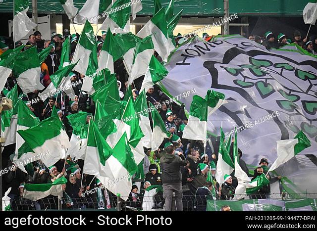 05 December 2023, Saarland, Homburg: Soccer: DFB Cup, FC Homburg - FC St. Pauli, round of 16, Waldstadion. Homburg's fans wave flags
