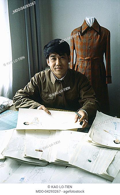 Chinese fashion designer Kao Lo-Tien drawing sketches in his workshop. China, 1979
