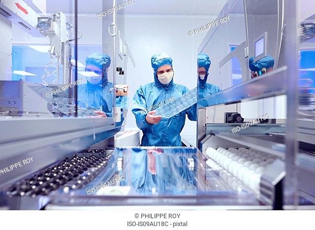 Male worker inspecting flex circuit in flexible electronics factory clean room
