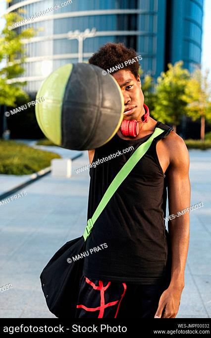 Portrait of a young man holding basketball in the city