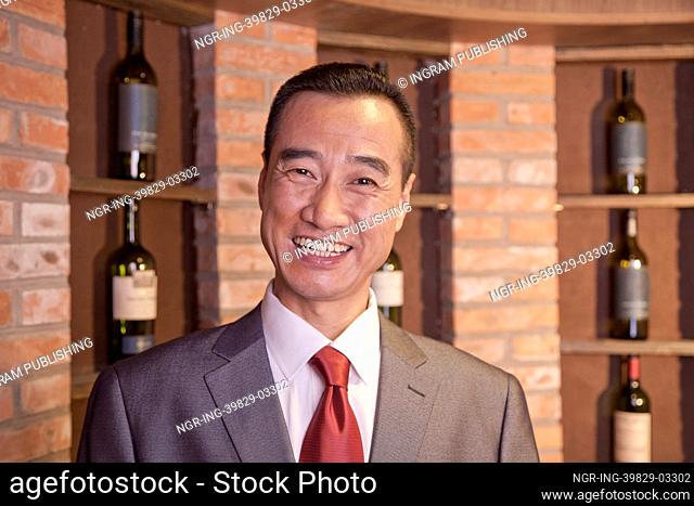 Smiling Businessman Standing by Wine Bottles