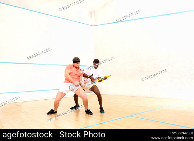 Men playing guitars on squash court. Handsome man playing game in squash and entertaining indoors after hard working day