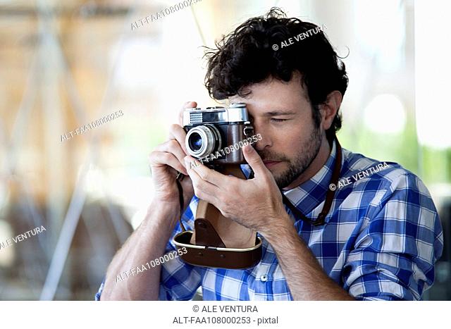 Man taking a photograph with a film camera
