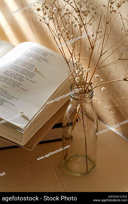 books and decorative dried flowers in glass bottle