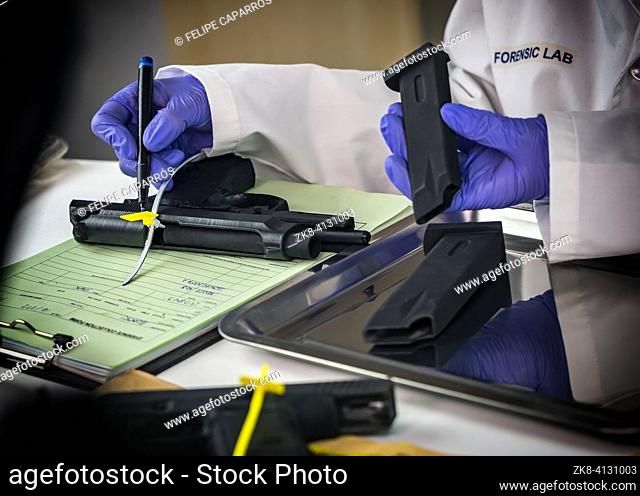 Police scientist notes serial number on sealed firearm in crime lab, conceptual image
