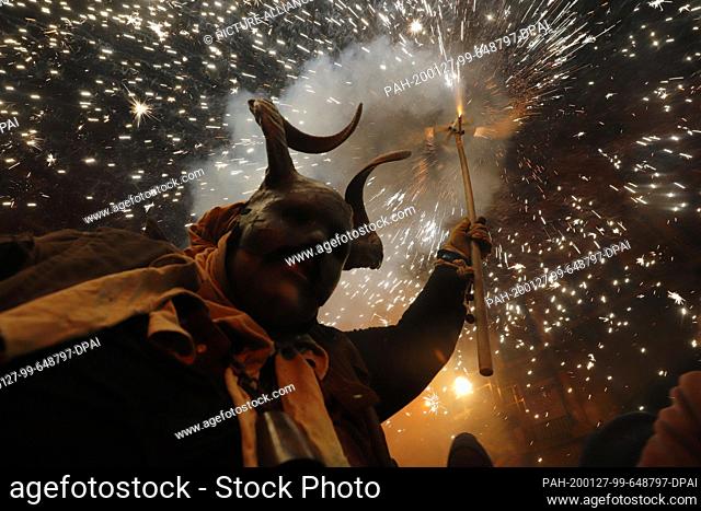 dpatop - 26 January 2020, Spain, Palma: A man disguised as a demon holding fireworks walks among the people during the traditional Correfoc (firewalk) in the...