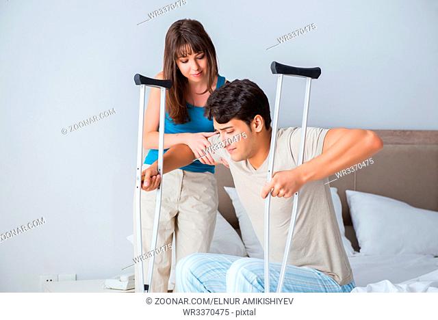 Young wife supporting husband on crutch after injury