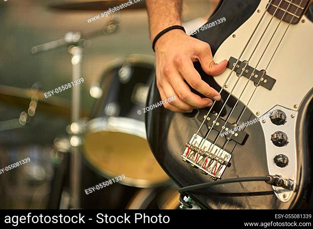 Detail of a bass player who plays his eacoustica bass at a live rock music concert