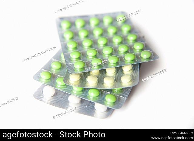 Close-up of green and white tablets in blisters on white background