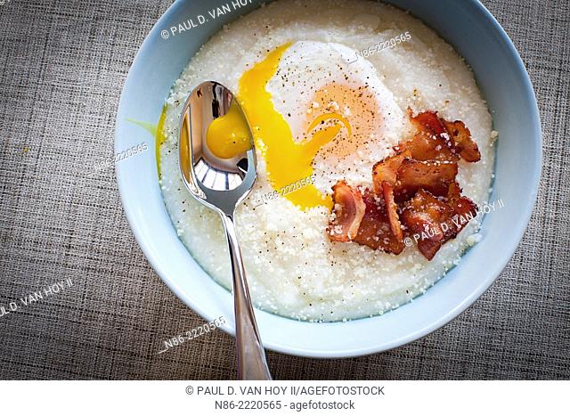 bowl of grits with bacon and egg on top