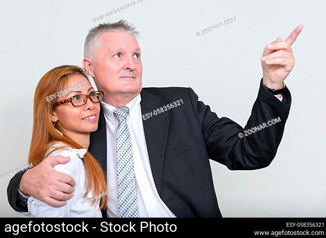Studio shot of senior businessman and mature Asian businesswoman together against white background