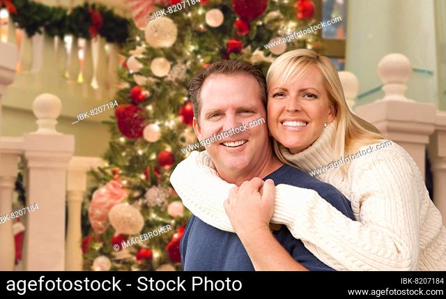 Caucasian couple hugging in front of decorated christmas tree