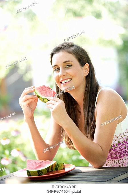 Young woman eating water melon in garden
