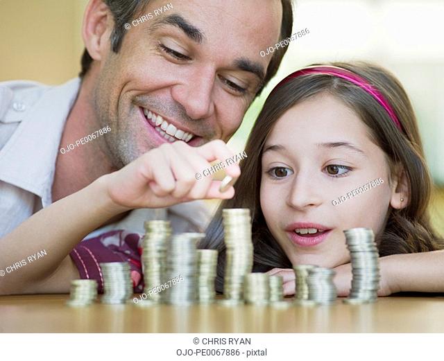Father watching daughter stack coins