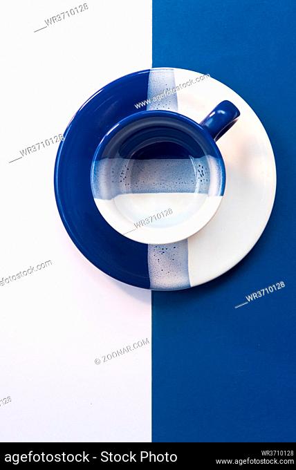 Blue and White empty coffee mug resting on a blue and white background