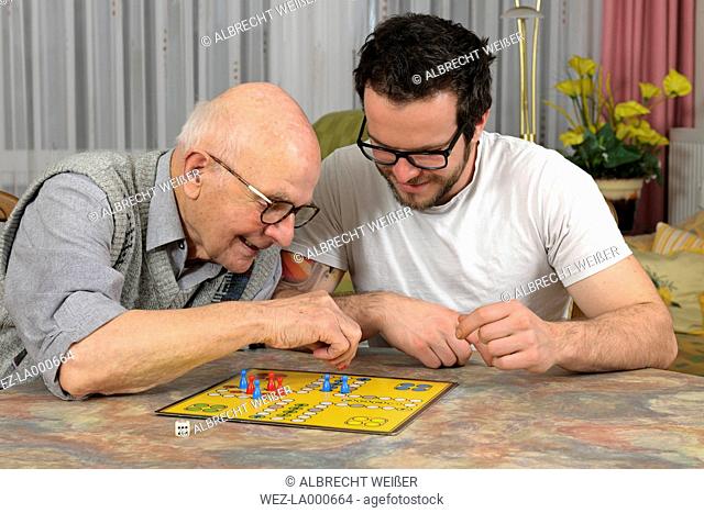 Grandfather and grandson playing together ludo at home