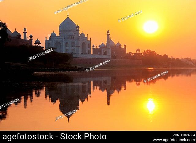 Taj Mahal reflected in Yamuna river at sunset in Agra, India. It was commissioned in 1632 by the Mughal emperor Shah Jahan to house the tomb of his favourite...