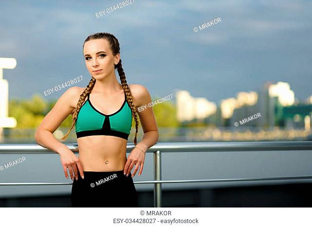 Concept: healthy lifestyle, sport. Attractive happy girl fitness trainer do outdoor workout at modern downtown urban area during sunset
