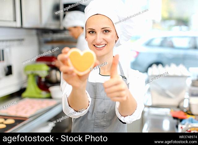 Pastry chef baking heart shaped cookies giving a thumbs-up