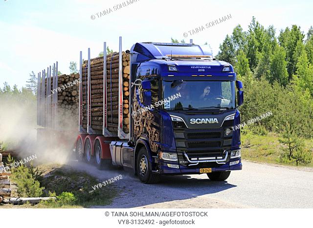 Test drivers wave as they drive Next Generation Scania R730 logging truck on rural road during Scania Tour 2018 in Lohja, Finland - May 25, 2018