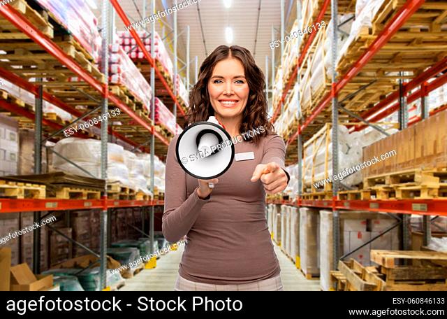 happy female worker with megaphone at warehouse