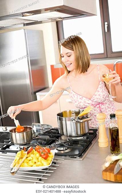 Attractive woman cooking spaghetti and tomato sauce