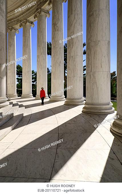 National Mall Thomas Jefferson Memorial A tourist strolls among the Ionic columns with long shadows cast by evening sun