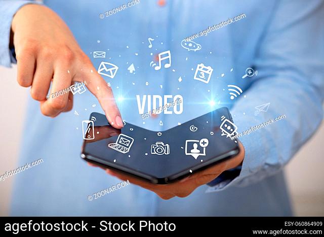 Businessman holding a foldable smartphone with VIDEO inscription, social media concept